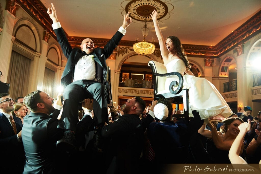 Jewish Bride and Groom lifting of the chairs at their wedding.