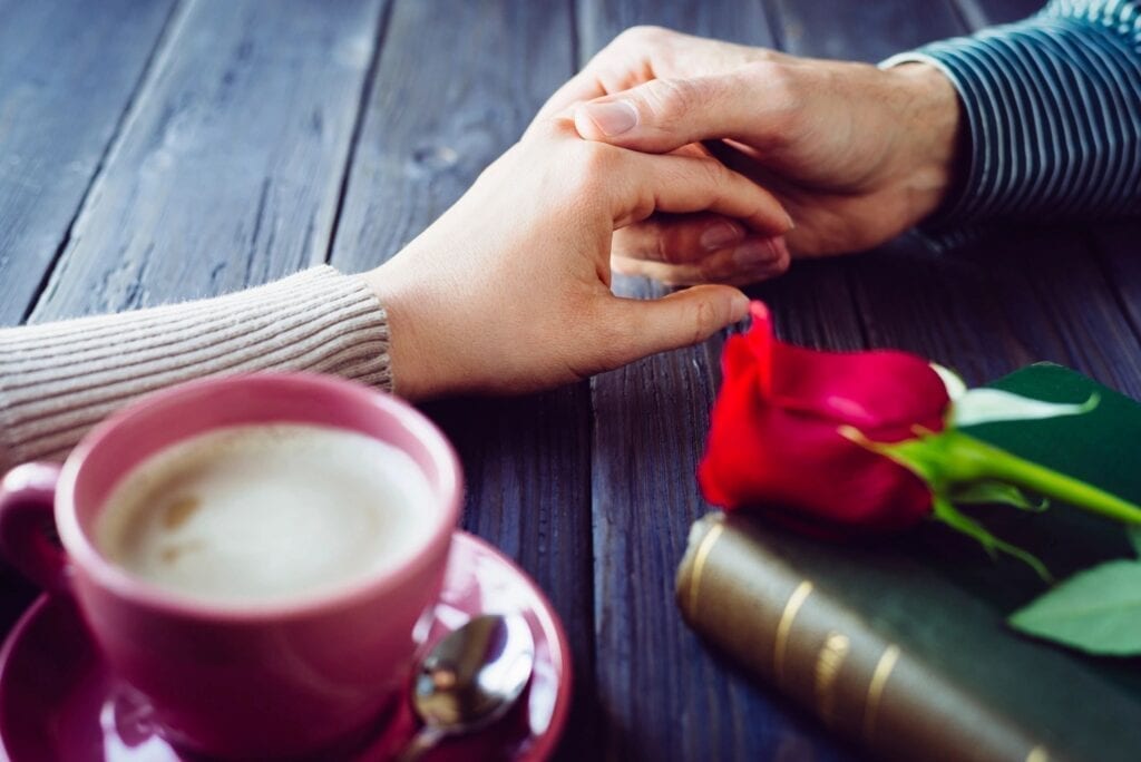 couple holding hands over coffee Strong Love