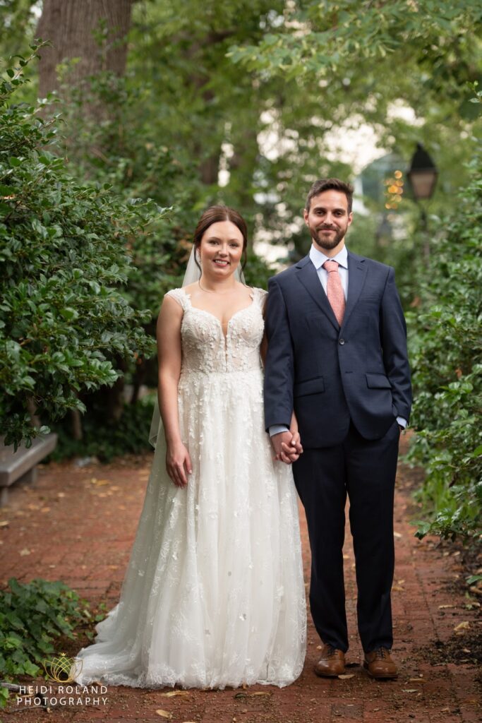 bride and groom hooding hands on brick path old city Philly